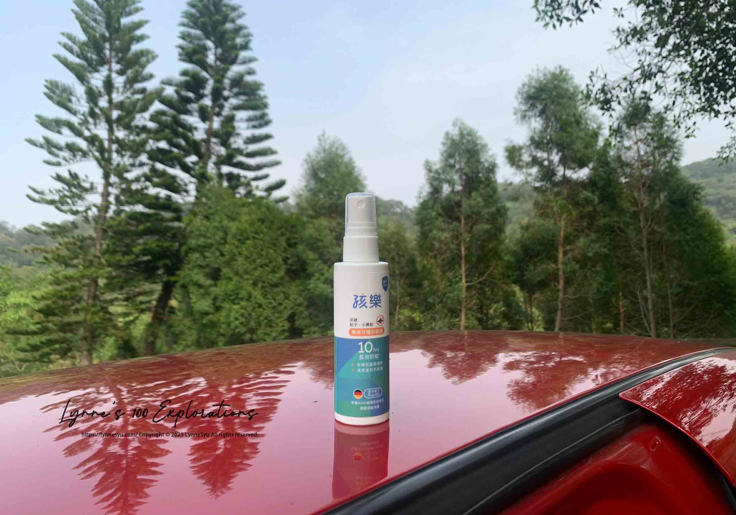 在森林中的紅色車子，車頂放著一瓶孩樂專業守護防蚊液，瓶身寫著可以對抗小黑蚊與長效性